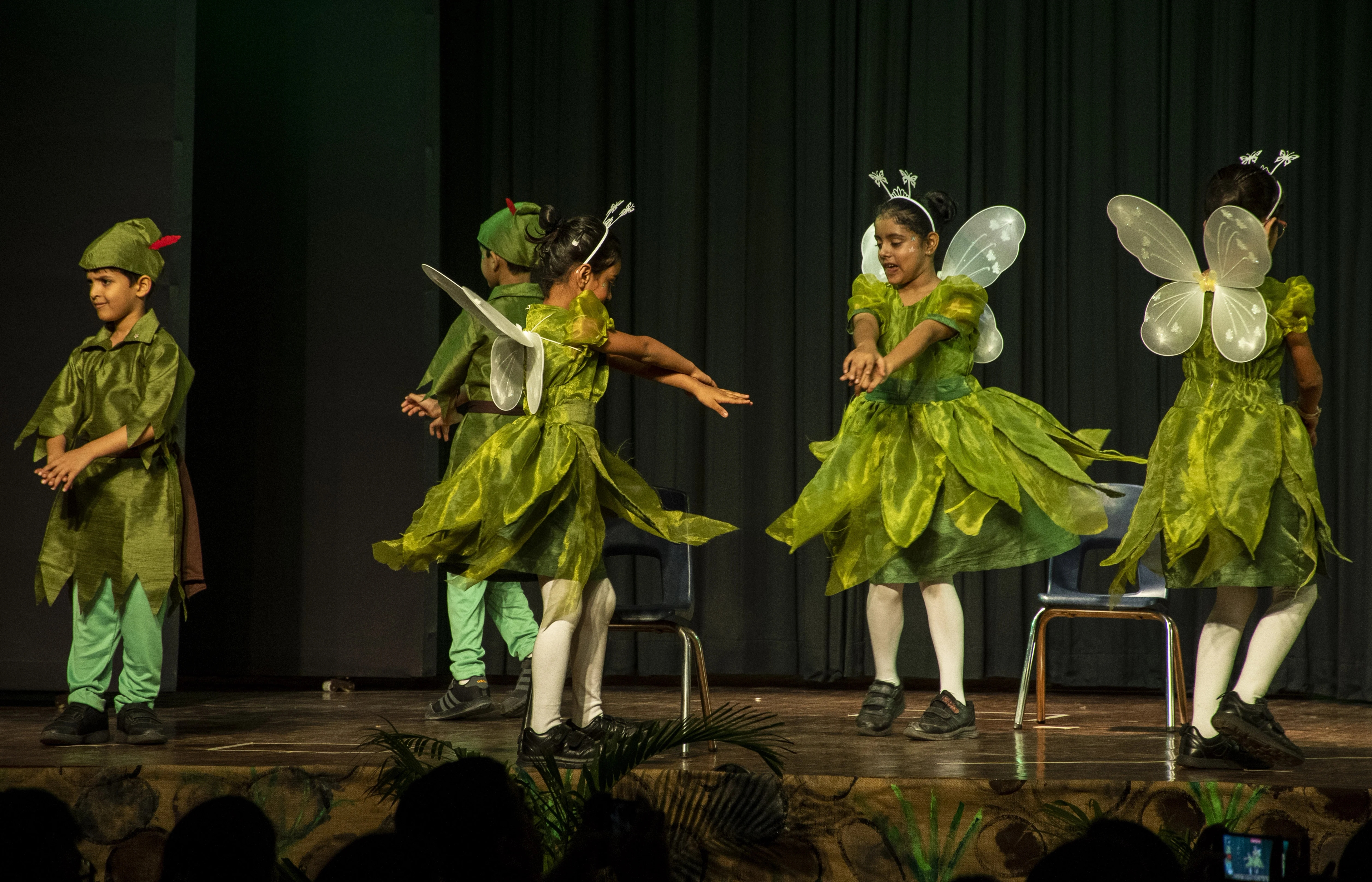 Junior students at a school performance with colourful stage lighting